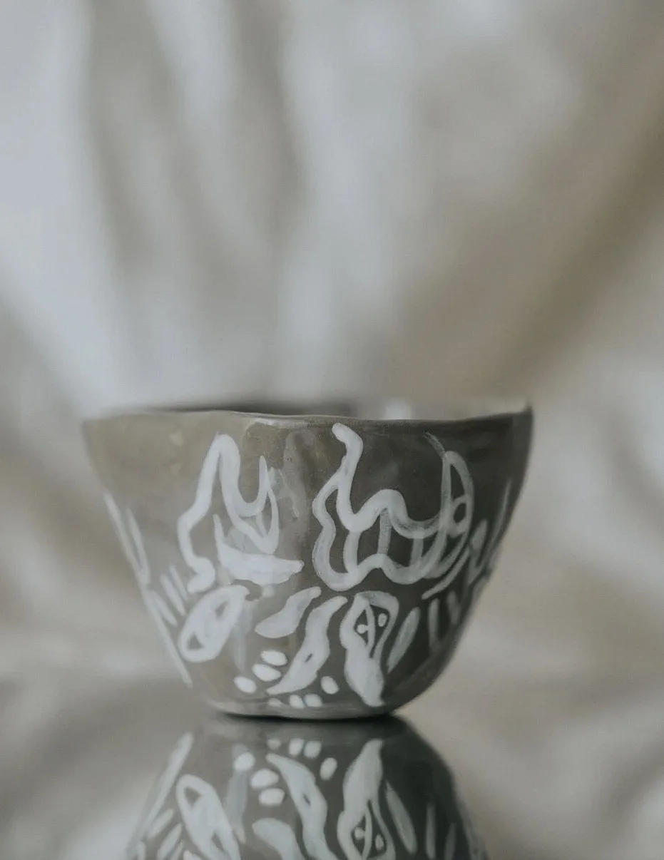 Beautiful handmade ceramic bowl featuring artistic white patterns on a reflective surface.