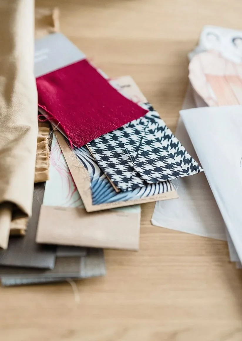 From above of ornamental fabric samples near paper sketches on wooden table in atelier