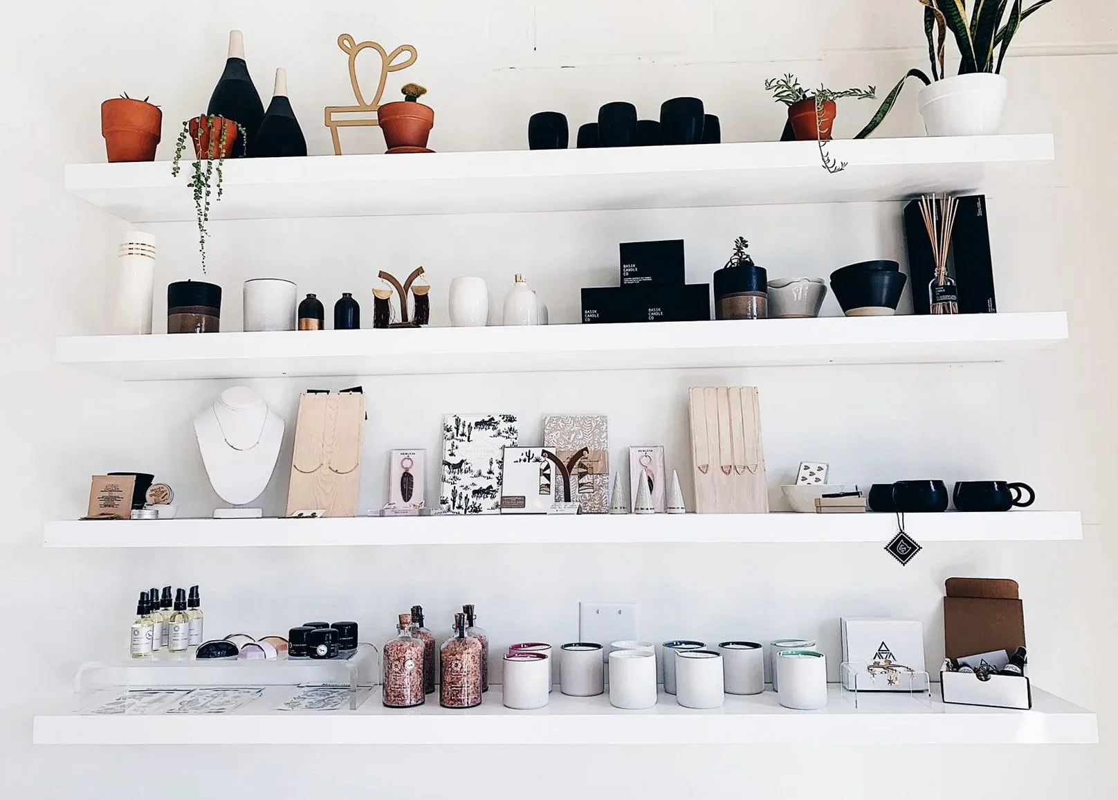 Minimalist shelves displaying plants, candles, and decor in a modern interior setting.