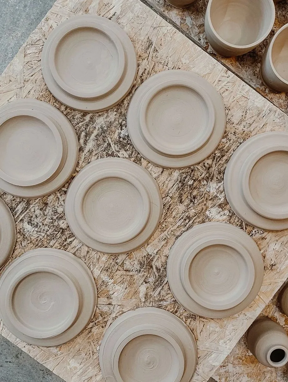 Handmade clay plates arranged on a wooden table, showcasing pottery craftsmanship.